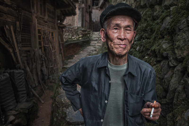 asia,asian,china,chinese,da zhai,da zhai terrace fields,dazhai,elderly,environmental portait,hat,longji,longji rice terraces,longsheng,male,man,old,older,people,portrait,smoking,standing,terraces,tian