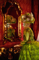 Venice Carnival model gazing into the mirror in an ornate bedroom.