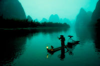 A Chinese fisherman rafting on the Li River before sunrise.