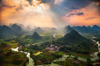 Light beams piercing the sky as seen from a hilltop.
