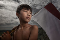 A young boy from West Java holding a flag over his shoulder.