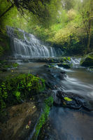 Vertical orientation of an exquisite waterfall framed by foreground trees.