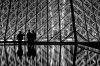 Silhouetted characters at the entrance to the Louvre.