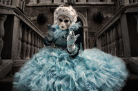 Blue costumed Carnival model calling from a stairway in Venice.