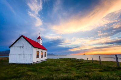 A classic Icelandic church sits proudly at land's edge as an epic sunset begins.