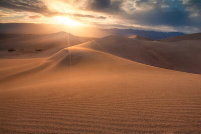 Intense sunlight covers the foreground dunes in warm light.