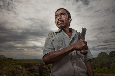 An Indonesian man posing with the machete used to farm his land.