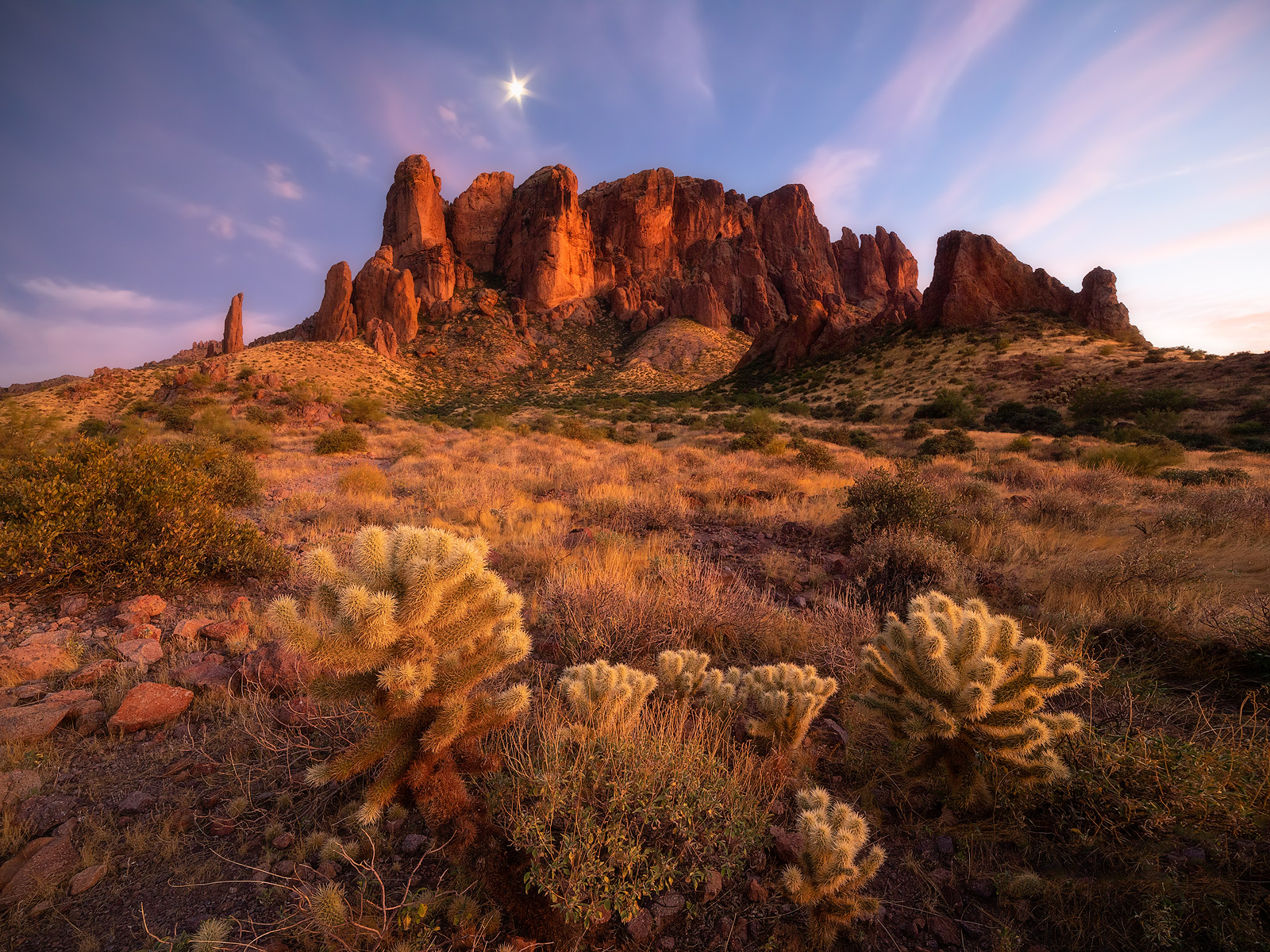 A twilight moon forms a star above Superstition Mountains.