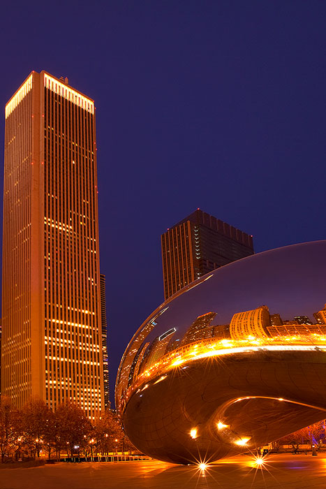 The Bean in front of a skyscraper at twilight