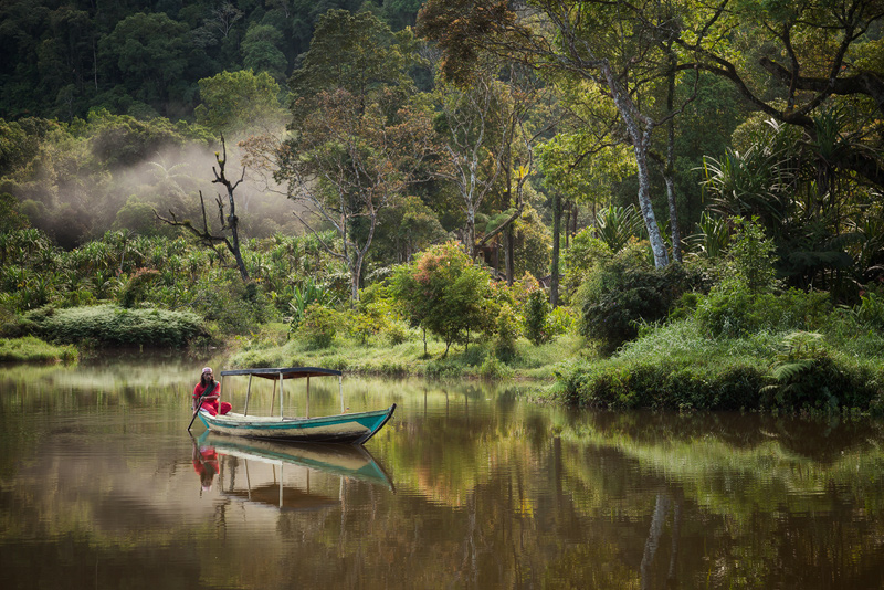 An Indonesian man takes an early morning boat ride on Indonesia's Situ Gunung