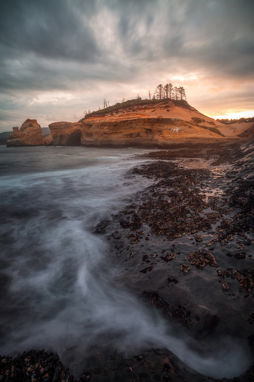 Retreating water forms a leading line to a distant cape on the Oregon coastline.