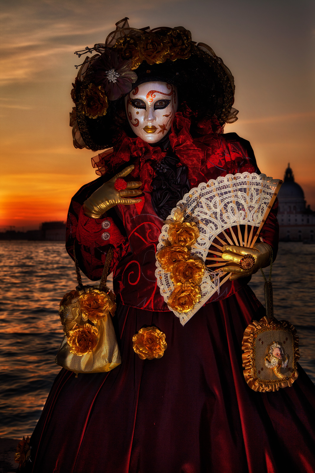 Mysterious looking Carnival model in front of a bright orange sunset.