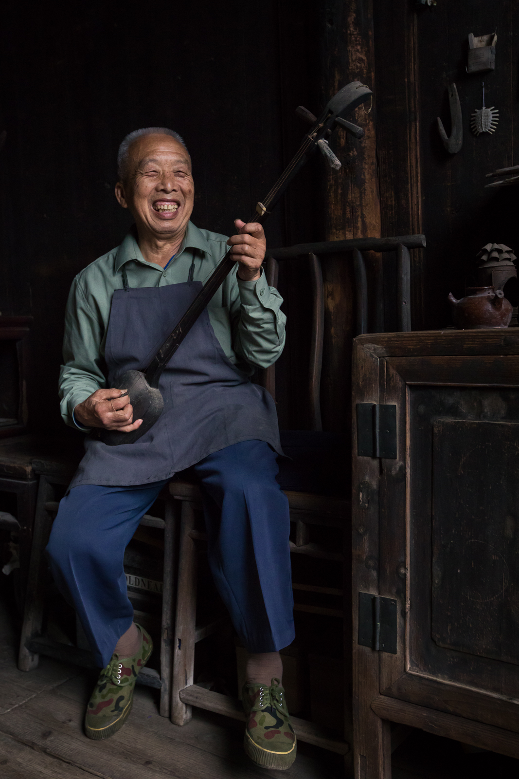 A Chinese man starts laughing while singing an old folk song.