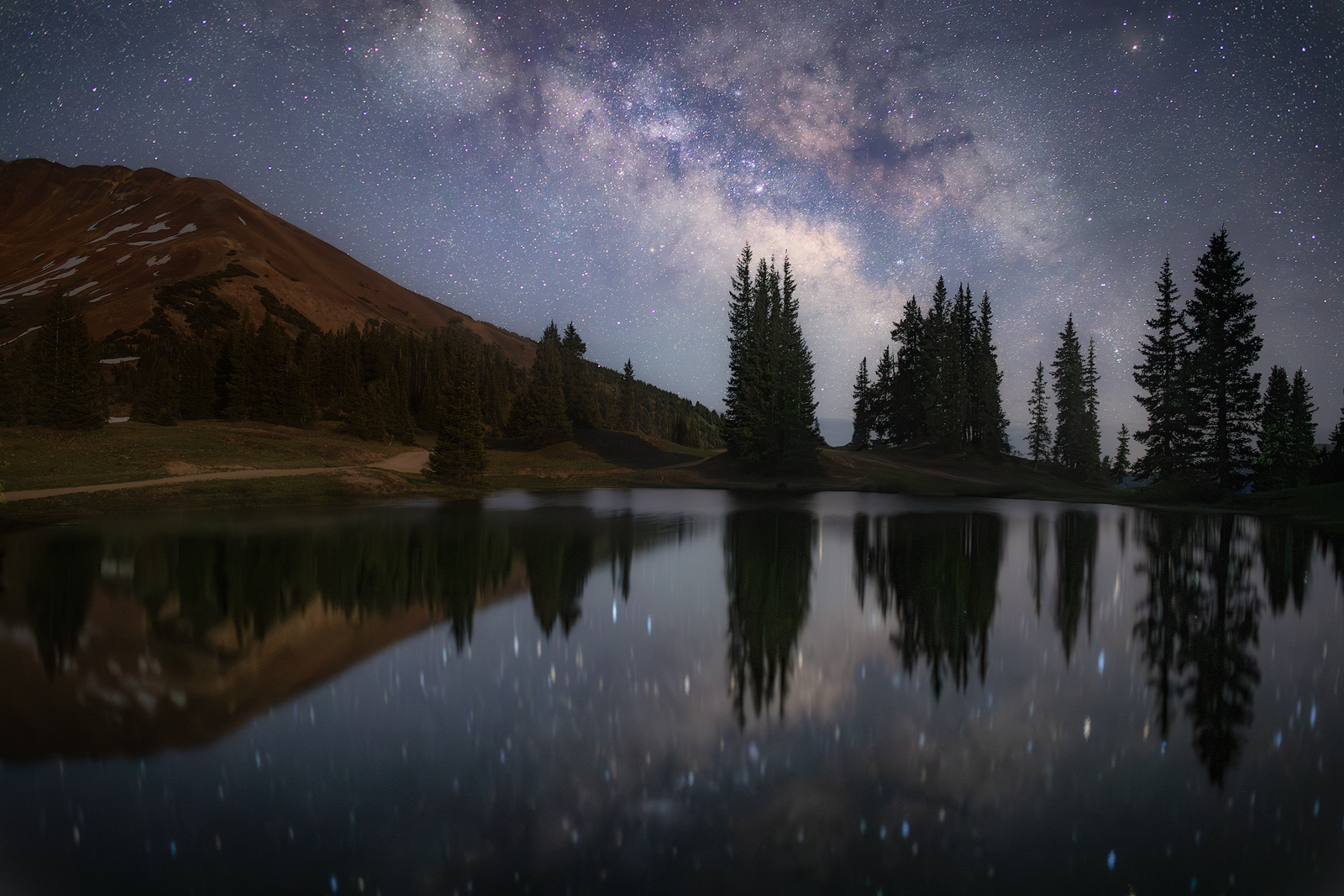 A pond at high altitude reflects the core of the Milky Way.