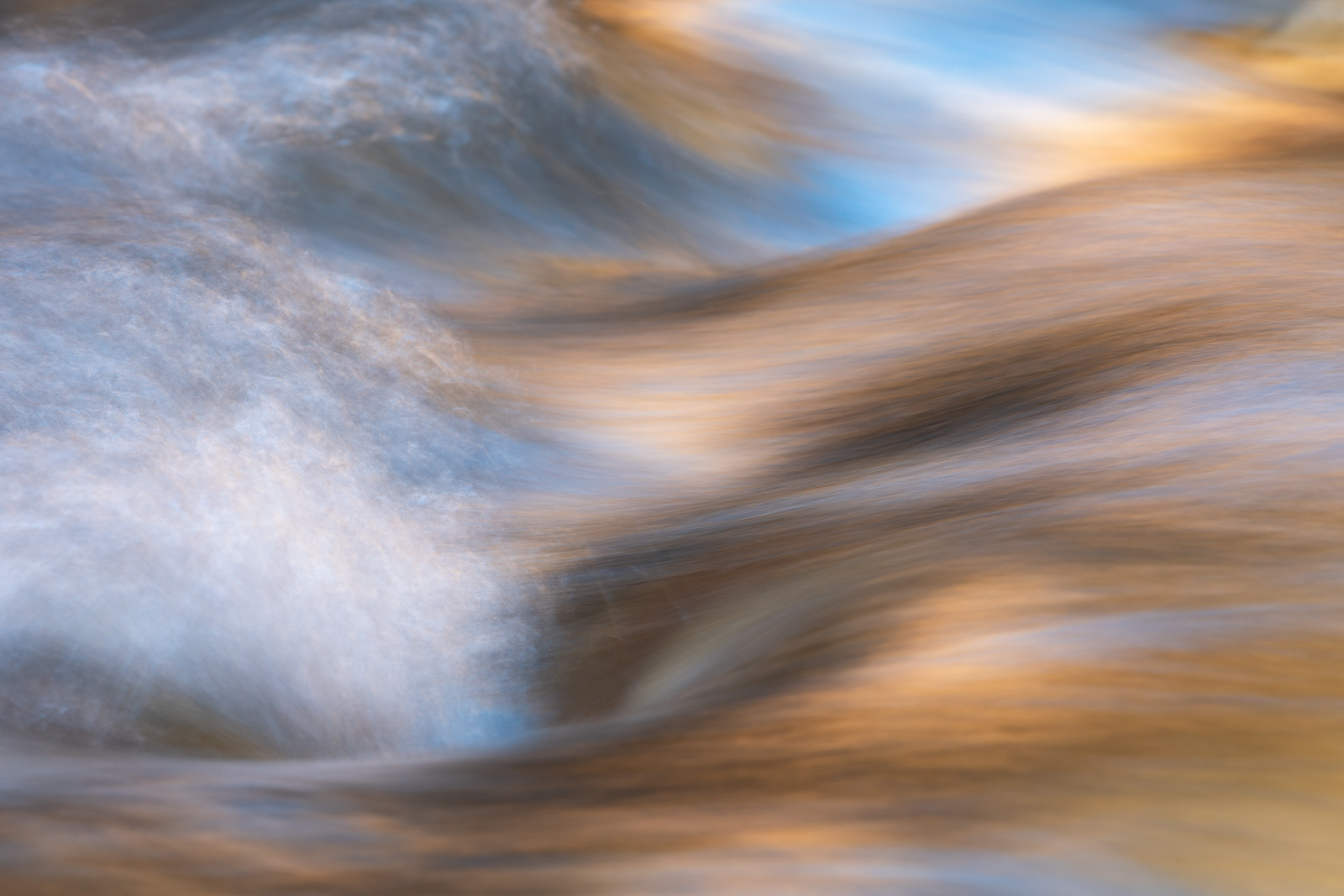 Golden, low-angled light catches ripples in a stream.