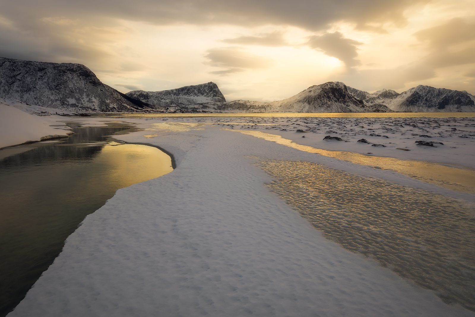Snow and ice cover a beach in Lofoten, Norway.