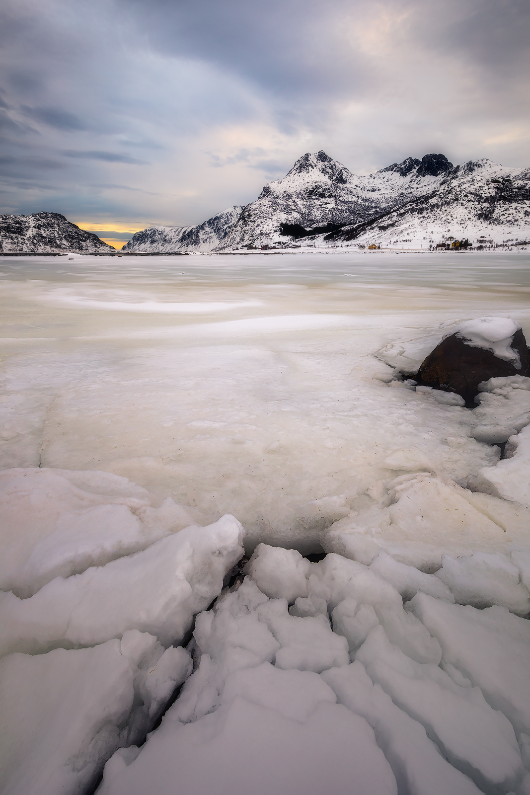 Cracks in the ice form leading lines to a snow-covered mountain.