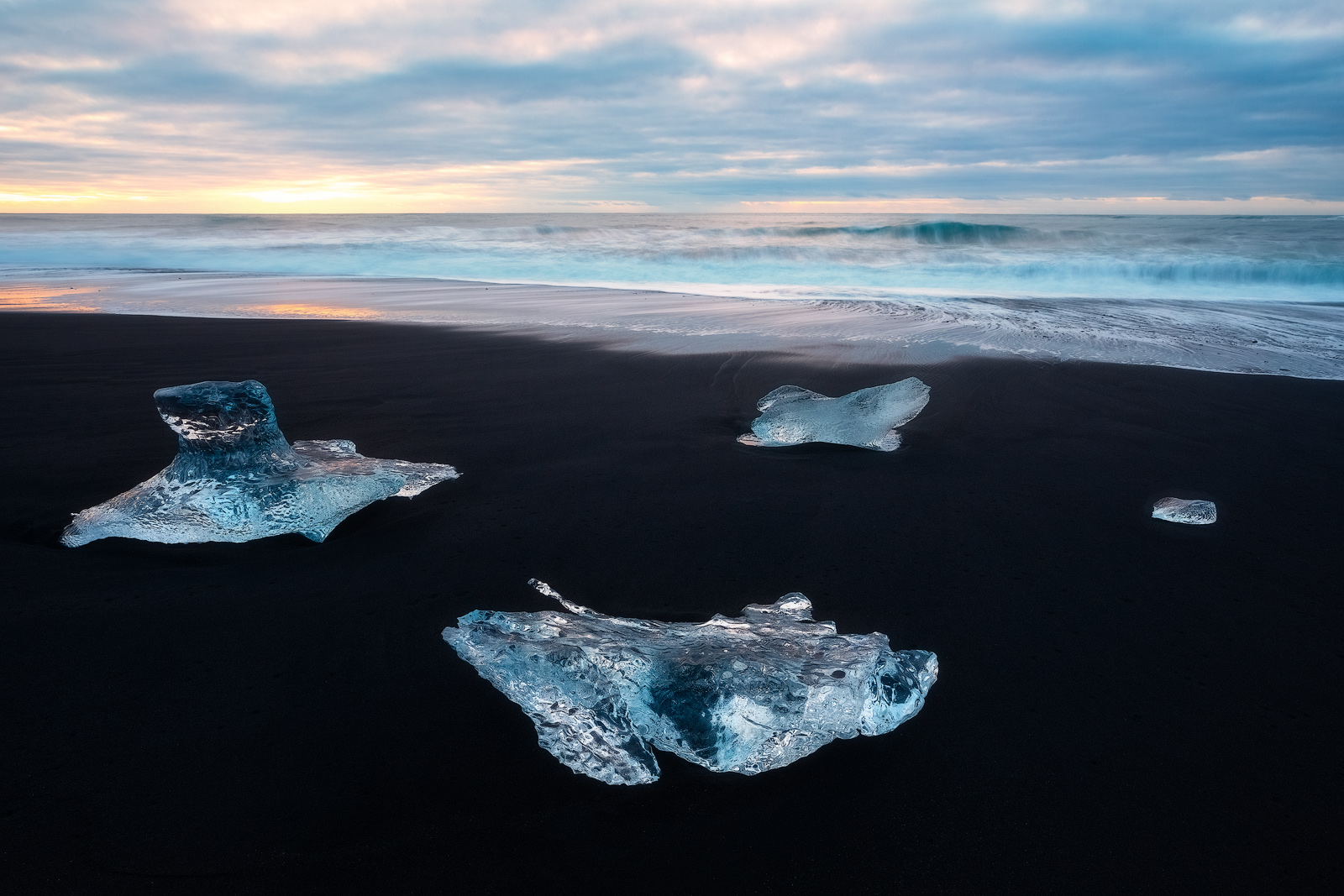 Beautiful blue icebergs washed up on a black sand beach in Iceland.
