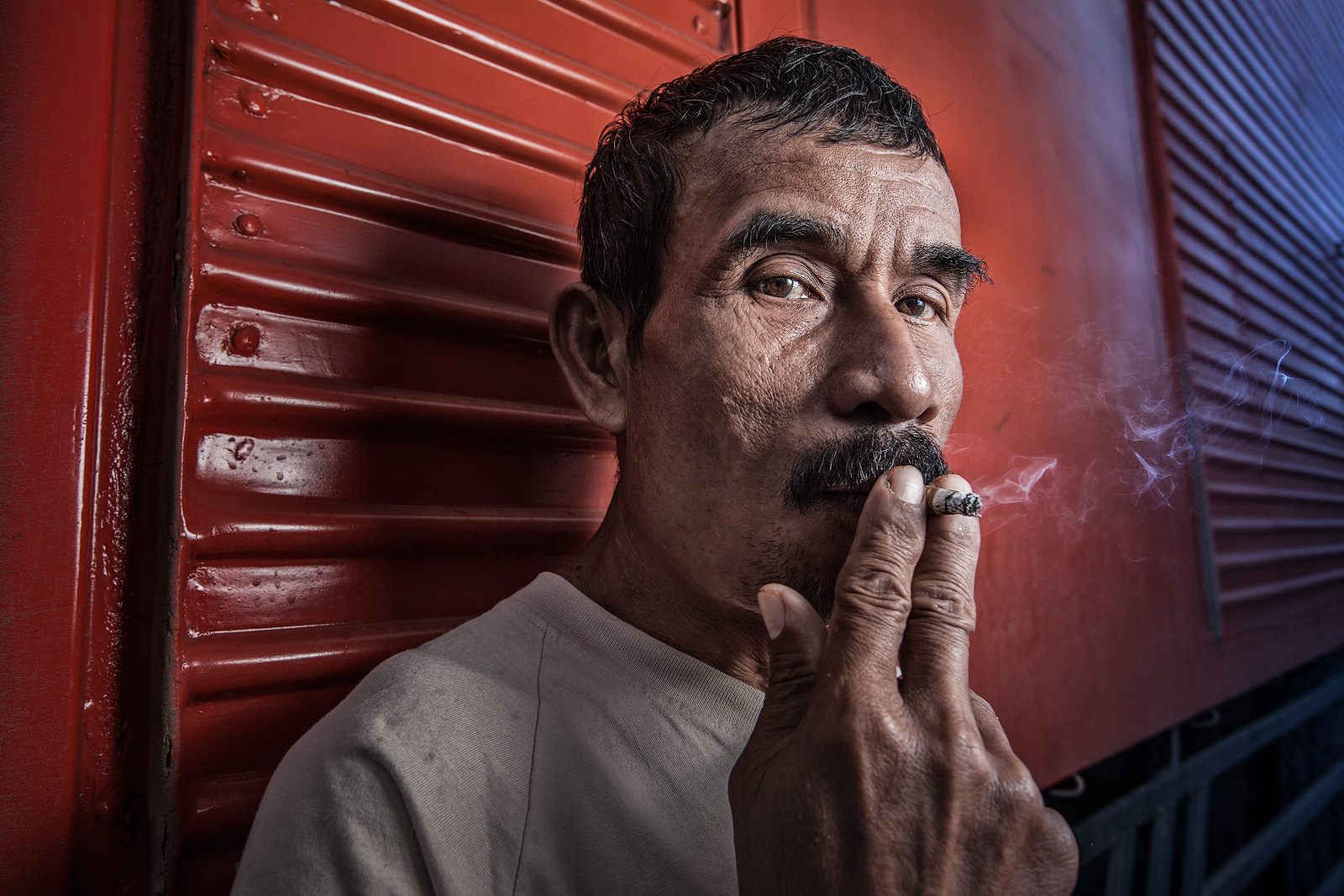 Indonesian dock worker taking a break behind a shipping container