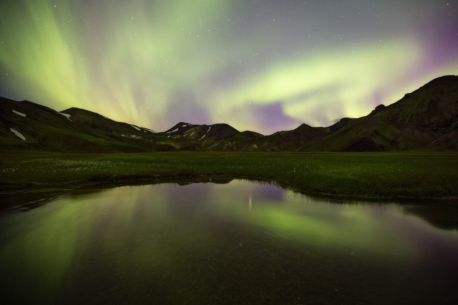 Northern lights over a small pond in Landmannalaugar