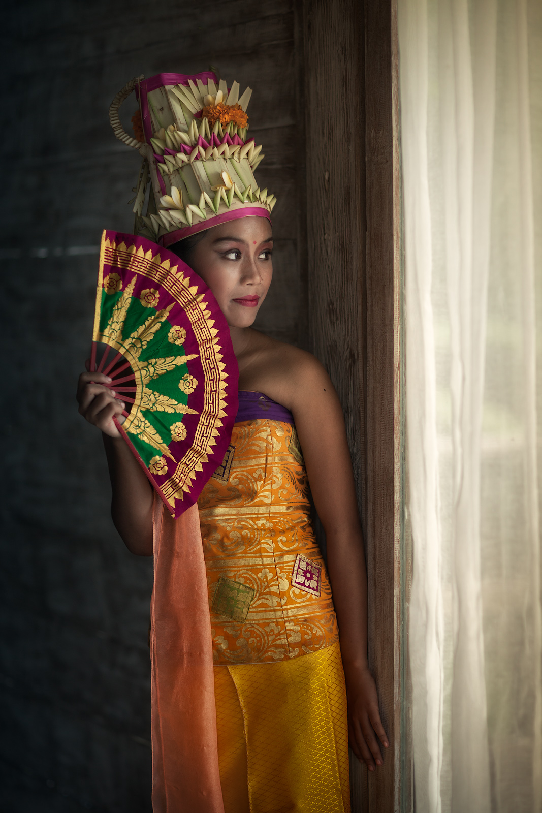 A Balinese dancer looking out the window