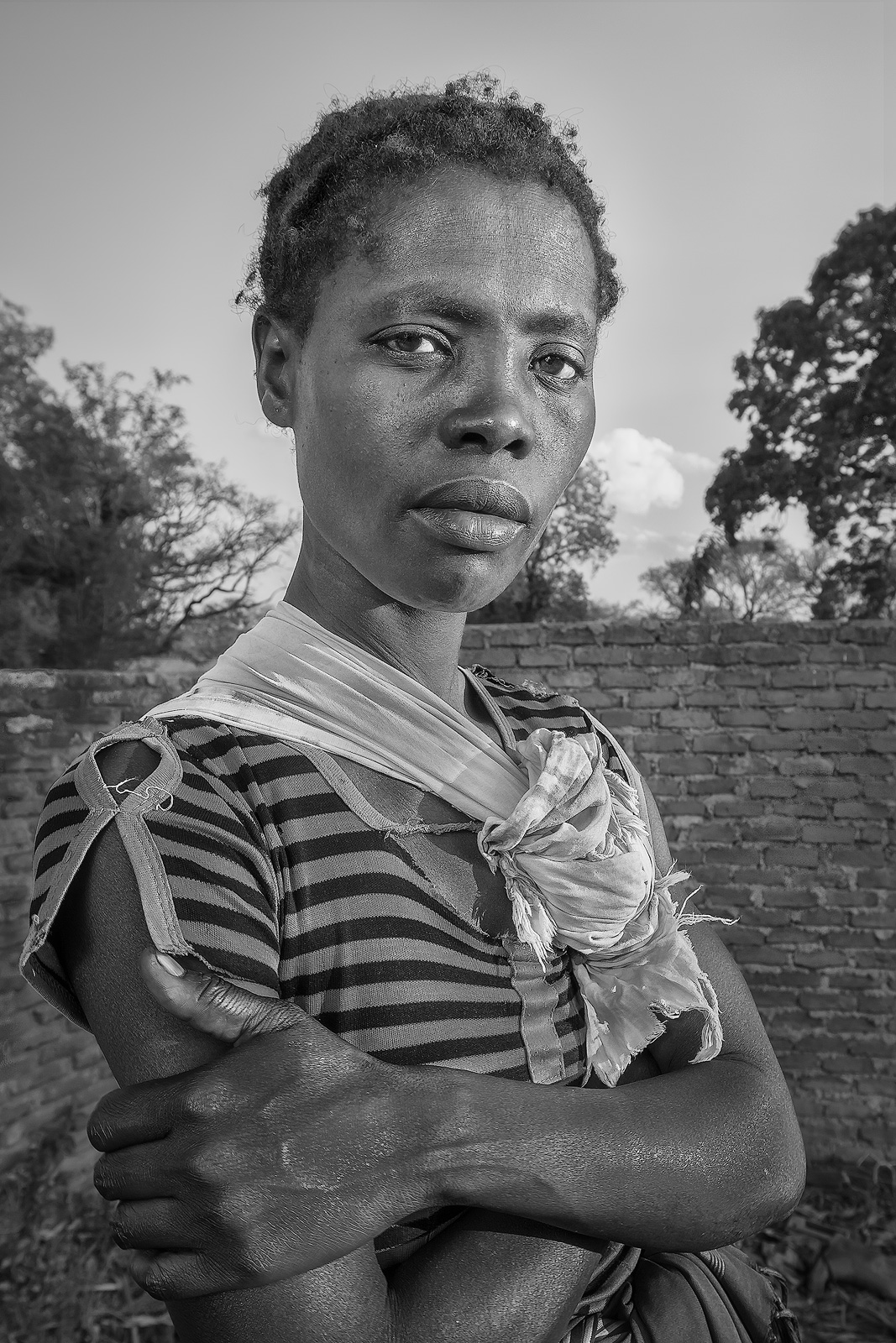 A young Malawian woman poses for the camera in early evening sunlight.