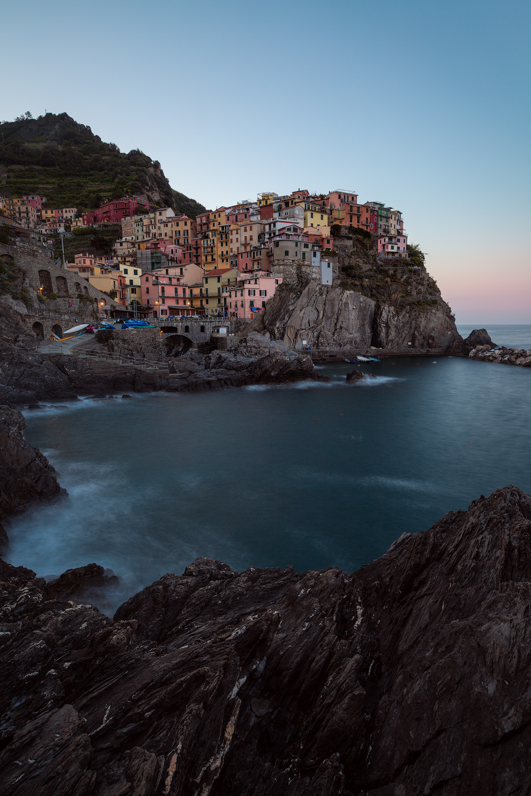 Cinque Terre's Manarola surronded by rock on a cloudless morning.