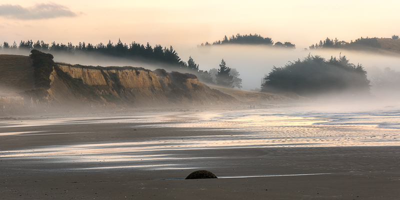 Fog rolling over the cliffs on Moeraki beach.