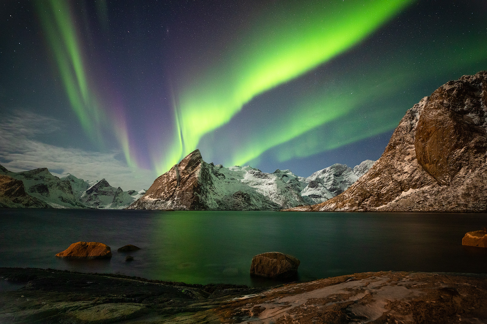 The aurora borealis over moonlit mountains at Hamnoy.