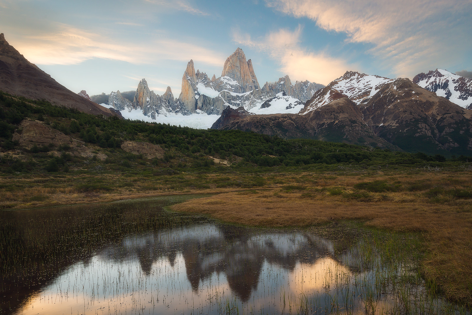 Glowing light on Mount Fitz Roy with a reflective marsh in the foreground.