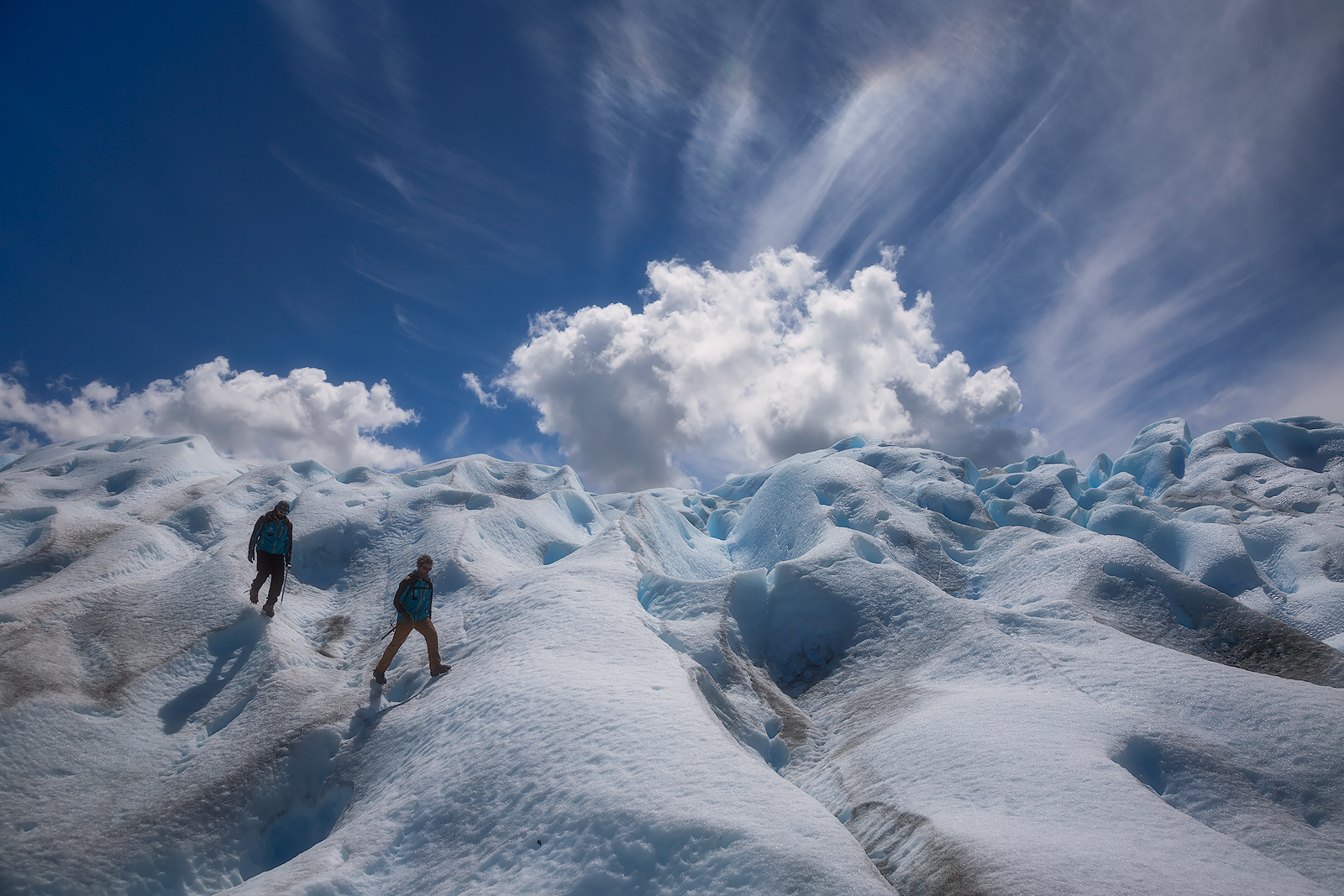 Unusual clouds forming behind two hikers on the Perito Moreno glacier.