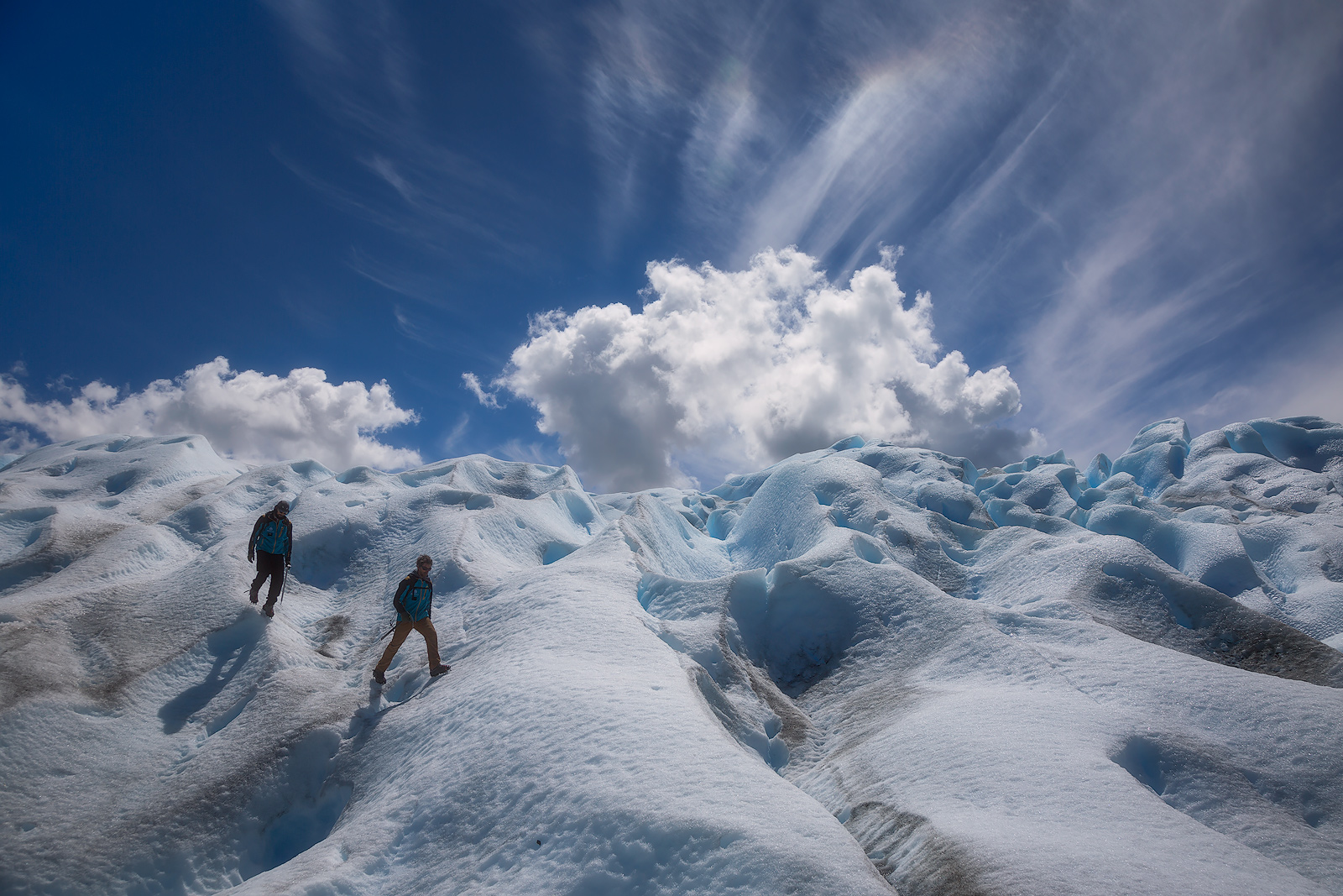 Unusual clouds forming behind two hikers on the Perito Moreno glacier.