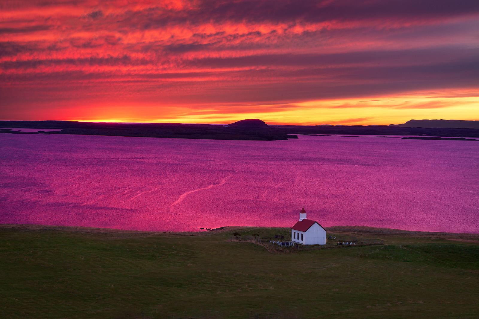 Red and white church over a lake turned purple at sunset