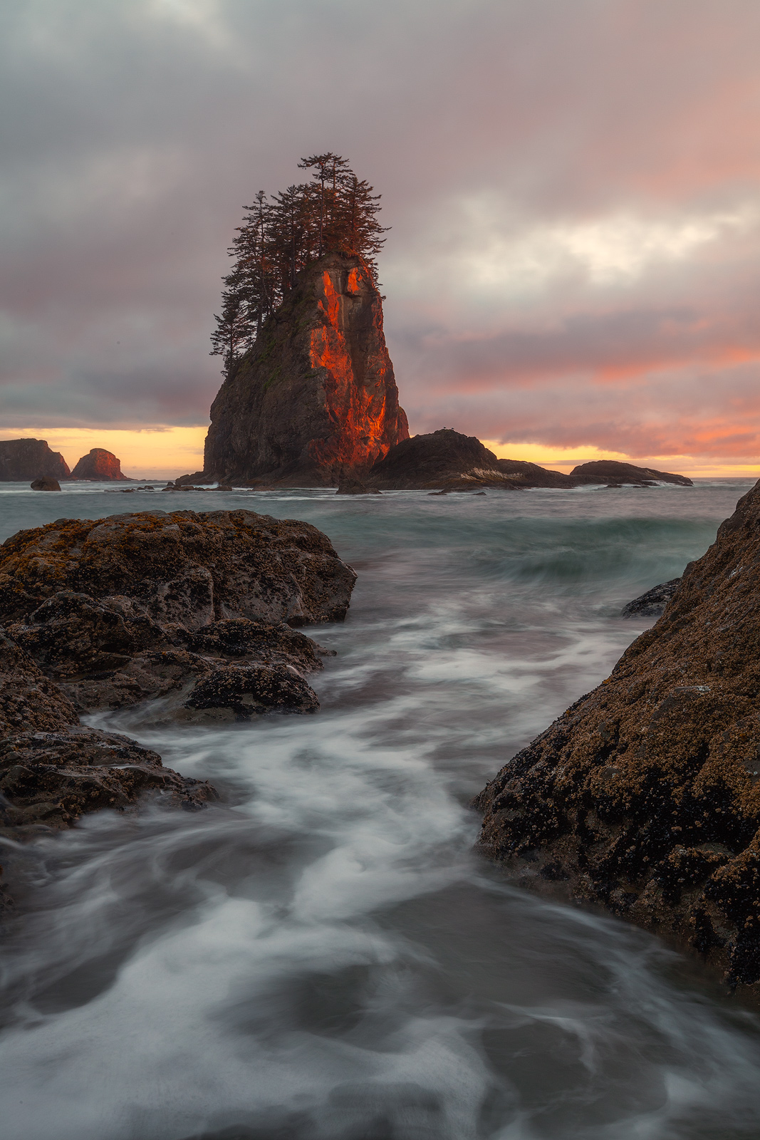 Low-angled light strikes the side of a sea stack during the last moment of sunset.