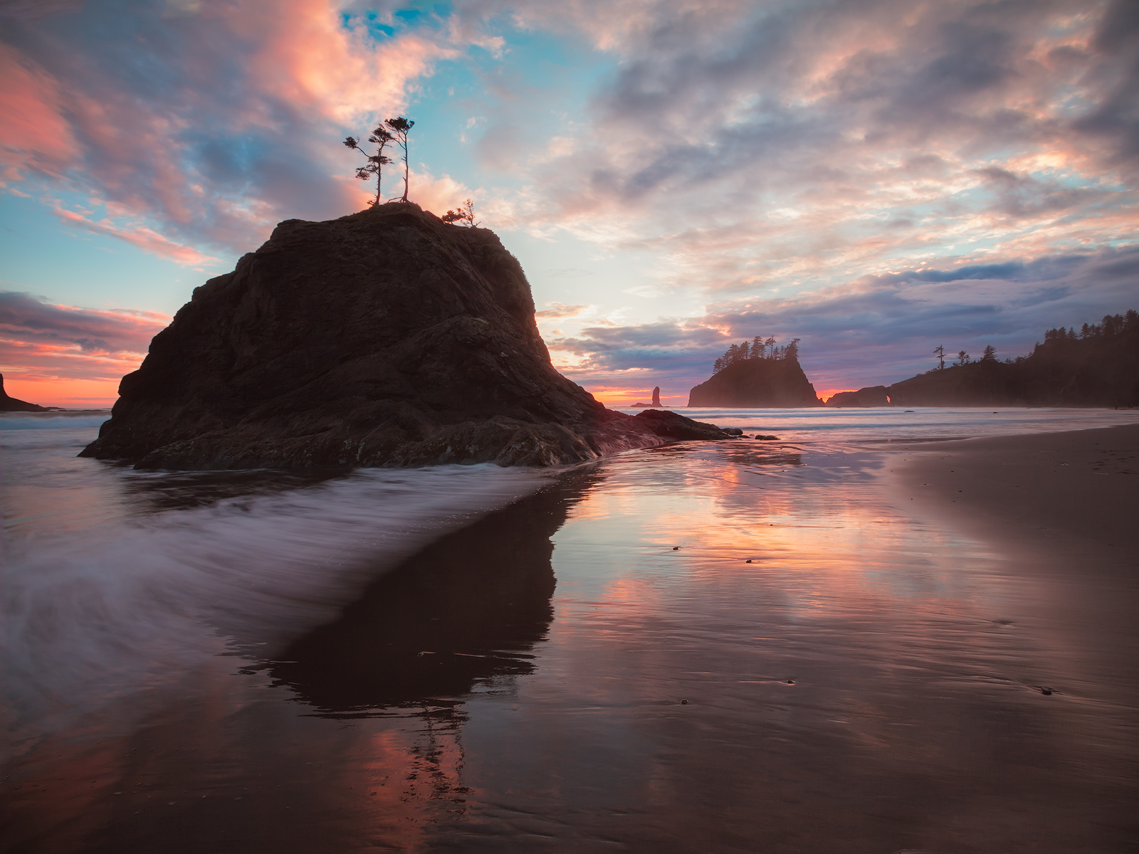 Sea stacks at Second Beach surrounded by reflections of the sunset in the retreating waters