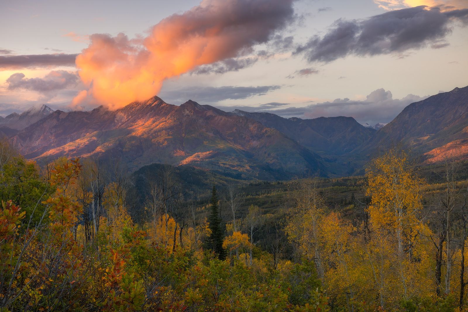 Sidelit clouds moving over mountain peaks during Autumn.