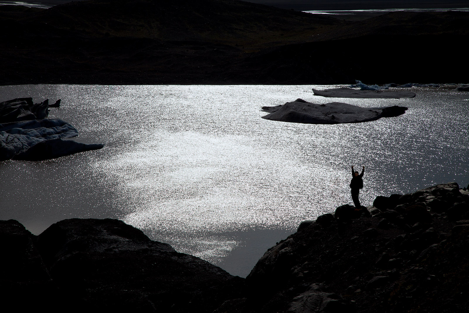 Silhouette of a hiker in front of a lake formed by glacier runoff