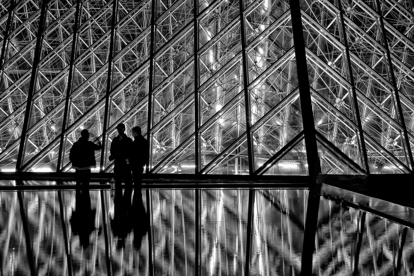 Silhouetted characters at the entrance to the Louvre.