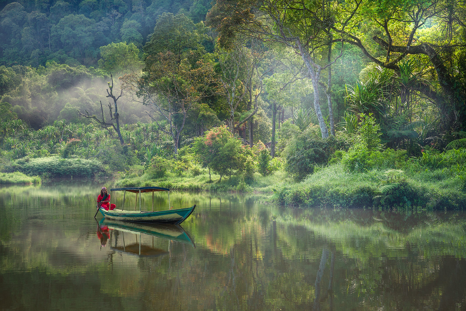 An Indonesian man takes an early morning boat ride on a remote lake.