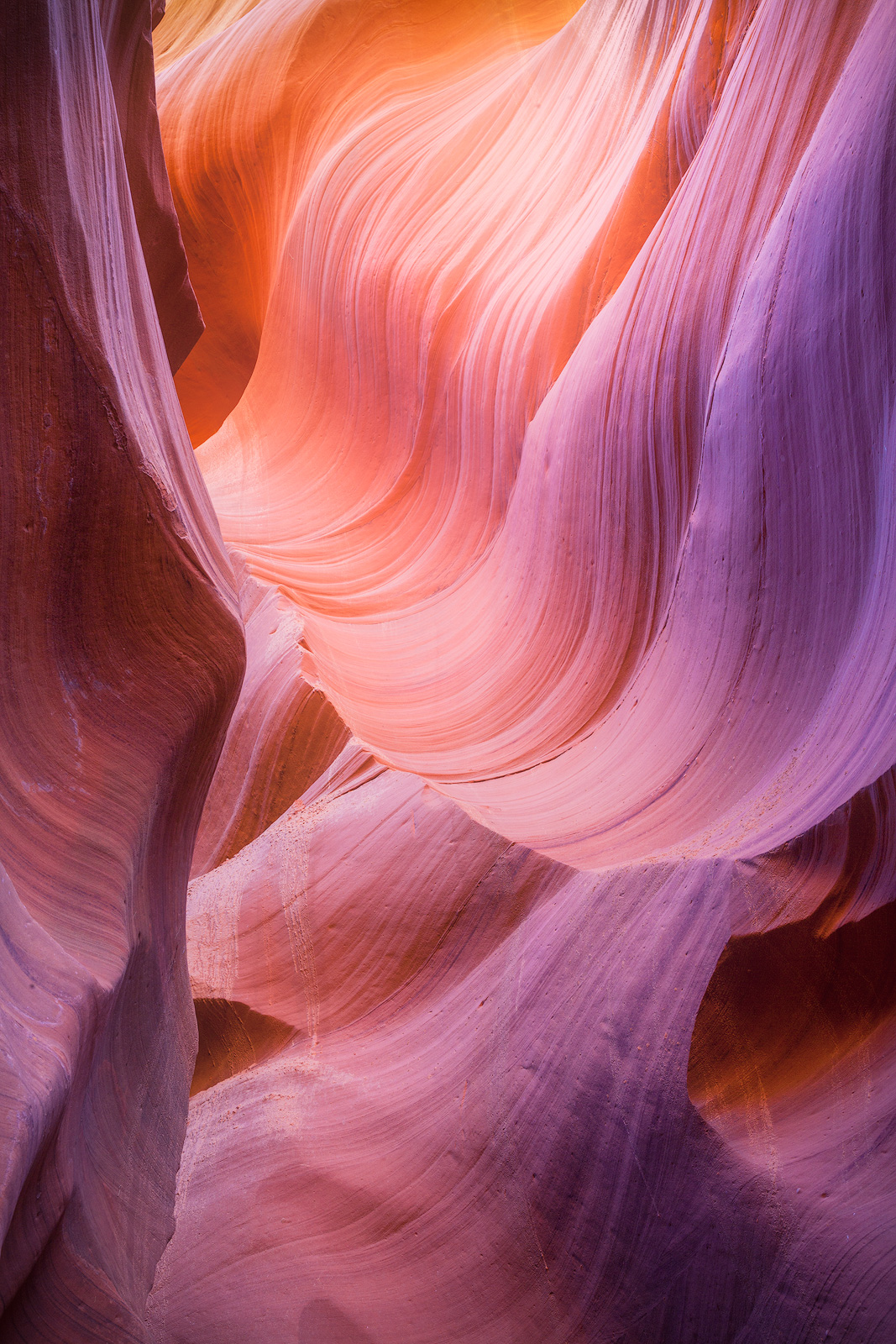 Deep magenta and orange wave-like formations in a slot canyon in the Navajo Nation.