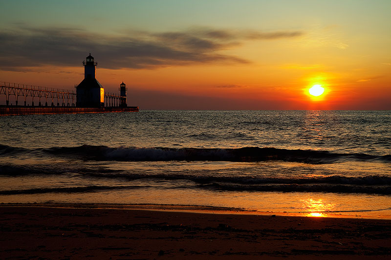 Gorgeous sunset behind a lighthouse and beach during Summer