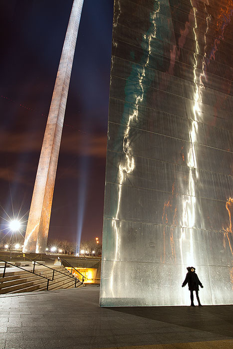Woman standing by the St. Louis Arch at night