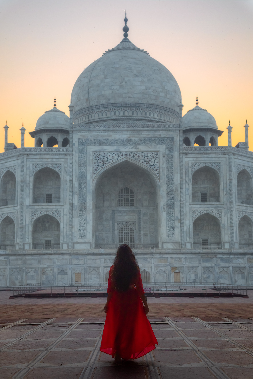 A beautiful girl in a red dress with a perfect morning view of the Taj Mahal.