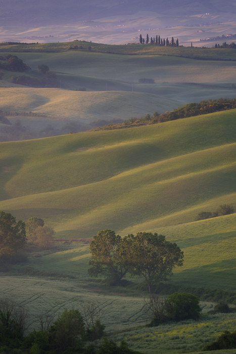 Sun hitting the side of hills in a Tuscany valley.