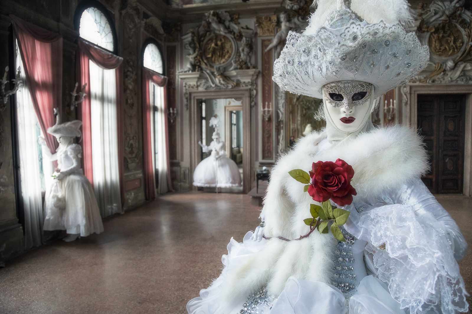 Three elegant Carnival models in an ornate palace ballroom.