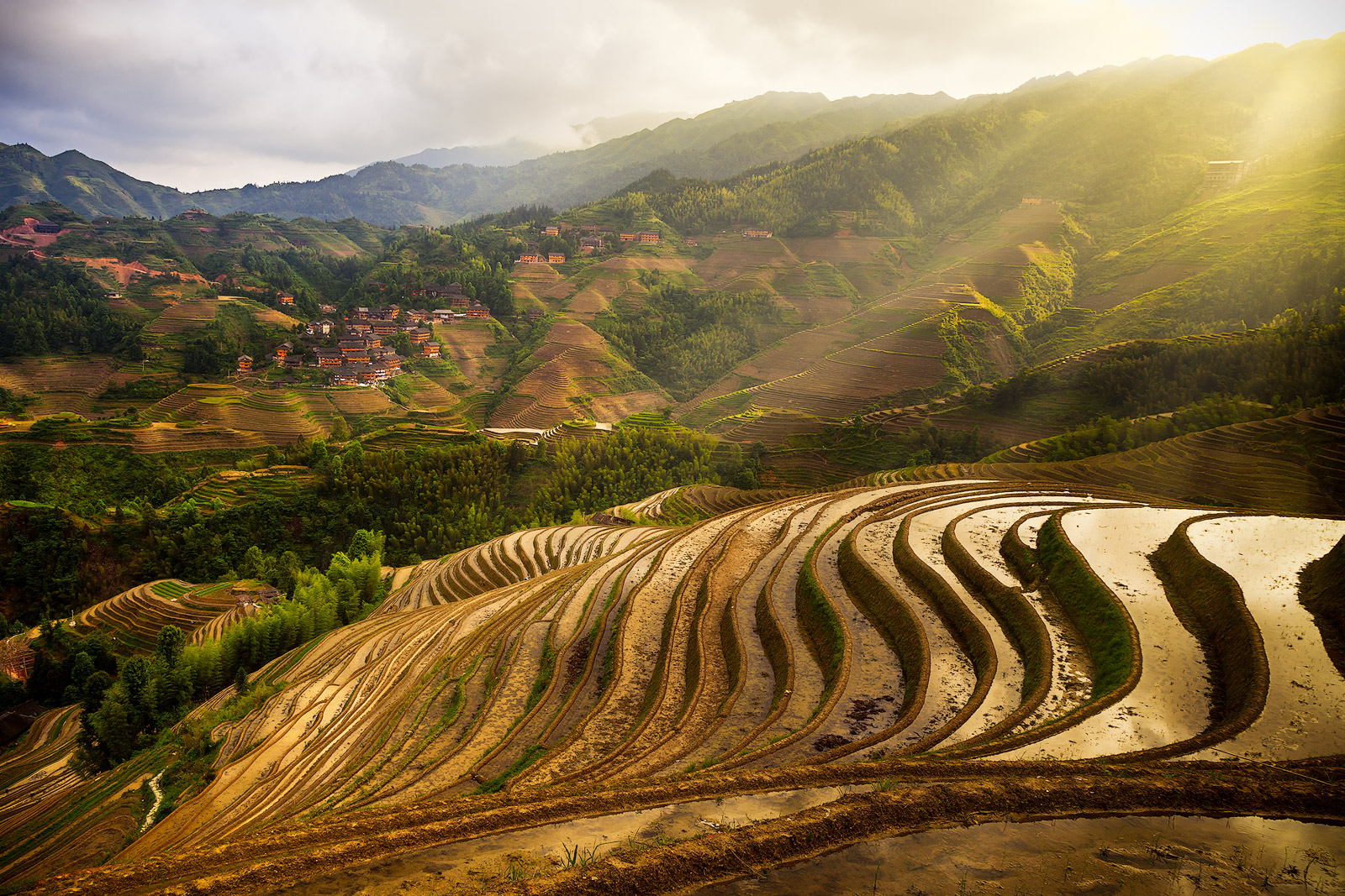 The sun breaking through cloud cover over China's incredible rice terraces.