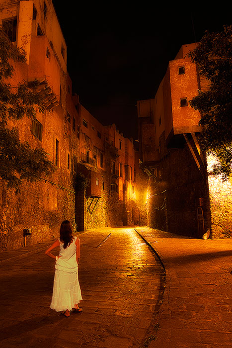 Woman wearing a white dress in a plaza at night